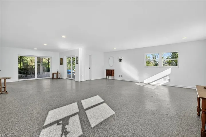 Unfurnished living room featuring healthy amount of natural light, recessed lighting, and speckled floor