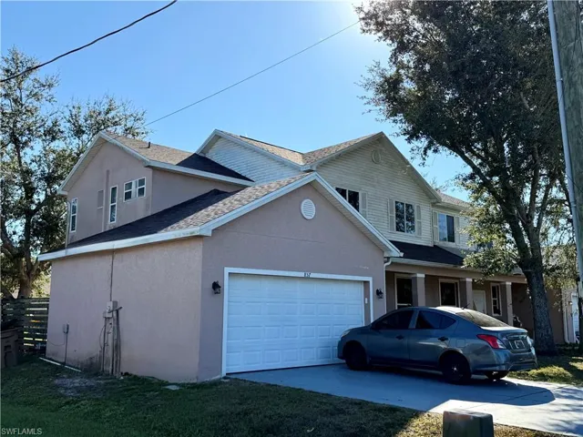 Traditional home featuring stucco siding, a shingled roof, driveway, an attached garage, and a porch