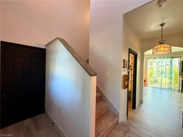 Staircase with wood finished floors and arched walkways