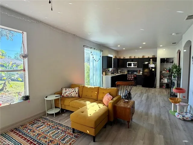 Living room with arched walkways, light wood-style floors, and recessed lighting