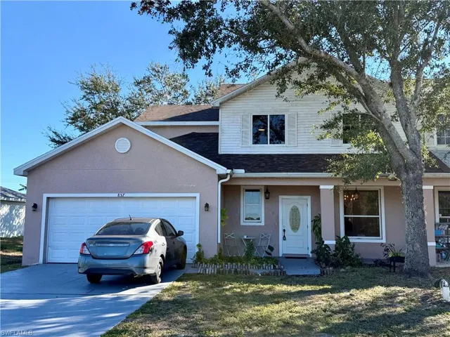 Traditional home with stucco siding, a garage, concrete driveway, a front yard, and roof with shingles