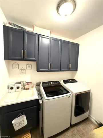 Washroom with washing machine and clothes dryer, cabinet space, and light colored carpet