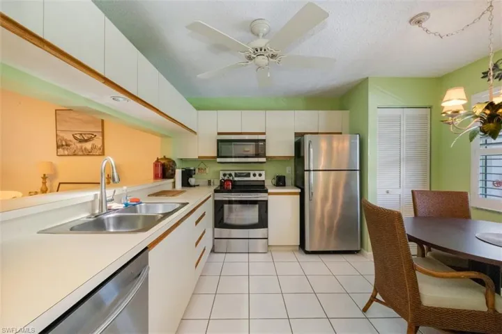Kitchen with stainless steel appliances, white cabinets, light tile patterned floors, light countertops, and a textured ceiling