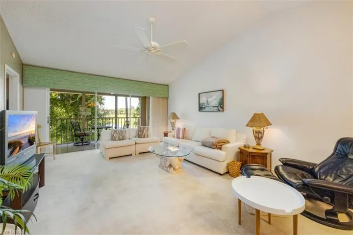 Living area featuring carpet, ceiling fan, and high vaulted ceiling