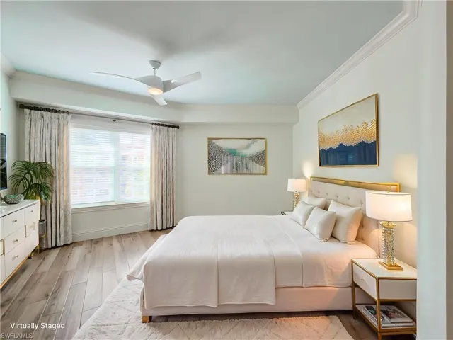 Bedroom featuring light wood-style floors, crown molding, and a ceiling fan