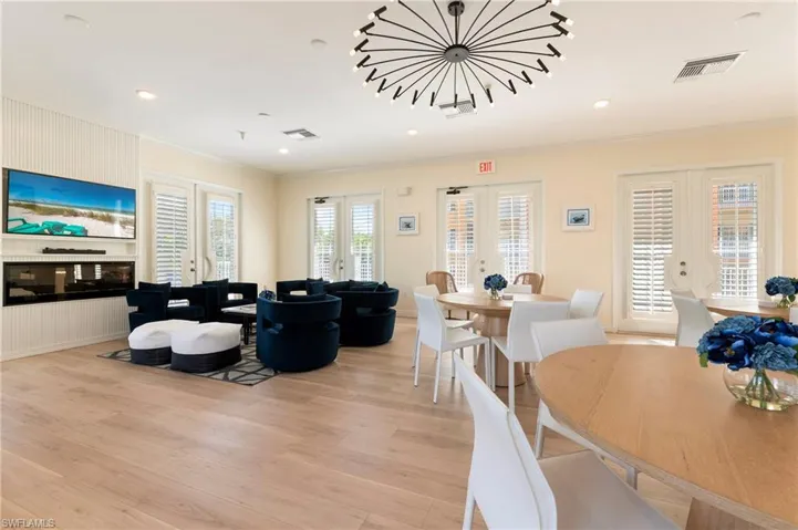 Dining room featuring french doors, light wood-type flooring, a glass covered fireplace, ornamental molding, and recessed lighting
