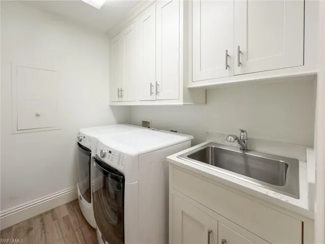 Laundry room featuring washing machine and clothes dryer, light wood-style floors, and cabinet space