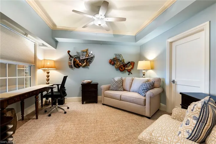 Office space featuring ornamental molding, a ceiling fan, and a raised ceiling