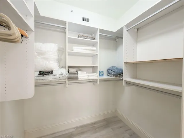 Walk in closet with light wood finished floors