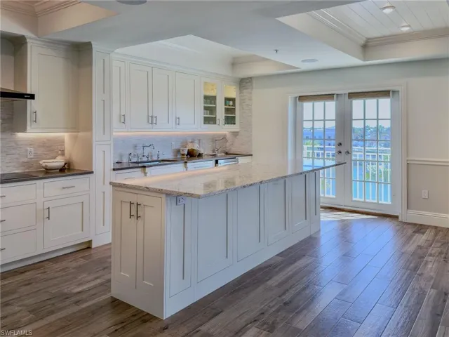 Kitchen featuring crown molding, white cabinets, glass insert cabinets, dark wood finished floors, and a tray ceiling