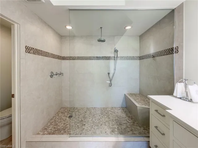 Bathroom with a walk in shower, vanity, and recessed lighting