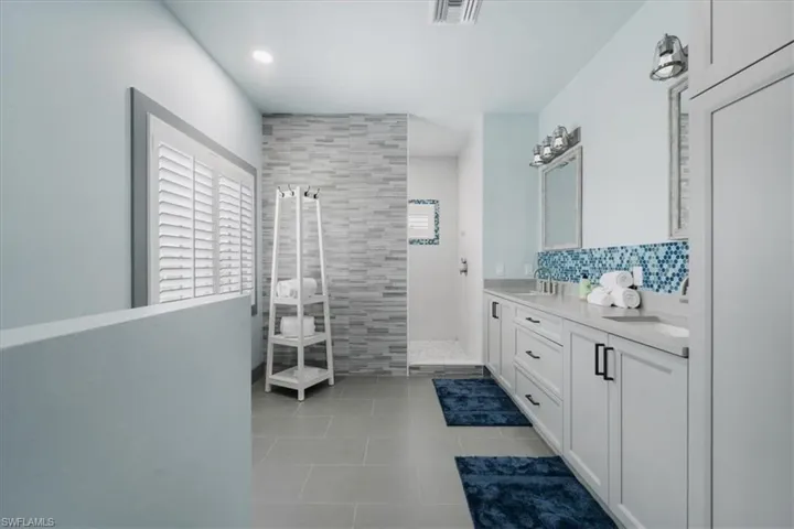 Bathroom with tile patterned floors, a tile shower, and double sink vanity