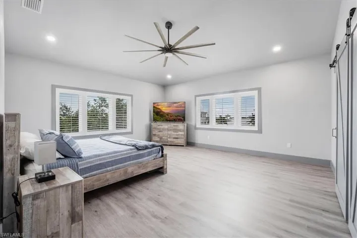 Bedroom featuring light wood-type flooring, a barn door, and multiple windows
