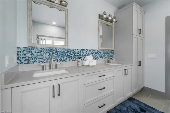 Bathroom with dual bowl vanity, tile patterned floors, and decorative backsplash