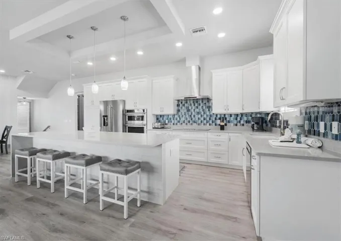 Kitchen featuring appliances with stainless steel finishes, wall chimney range hood, and a spacious island