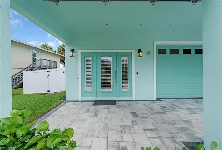 Property entrance featuring a garage, french doors, a patio, and a yard