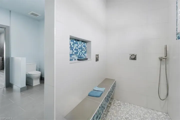 Bathroom featuring toilet, tile patterned floors, and a tile shower