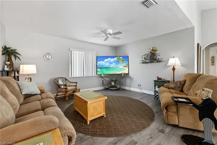 Living room with dark hardwood / wood-style flooring and ceiling fan