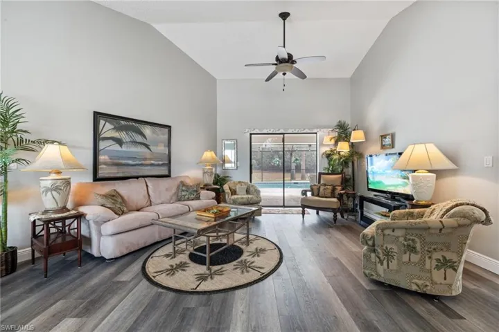 Living room with ceiling fan, dark hardwood / wood-style flooring, and vaulted ceiling