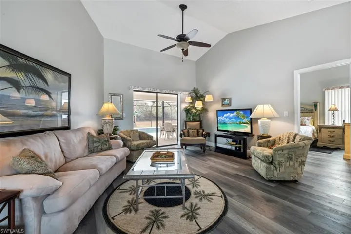 Living room featuring dark hardwood / wood-style floors, ceiling fan, and lofted ceiling