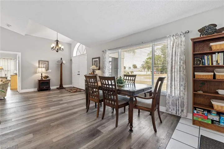Dining space featuring vaulted ceiling, dark hardwood / wood-style flooring, a textured ceiling, and an inviting chandelier