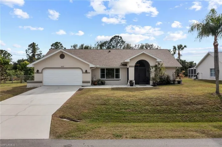 Ranch-style house with a garage and a front lawn