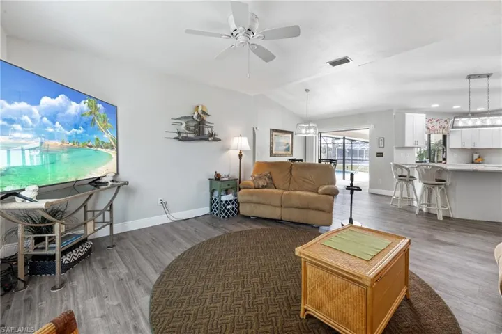 Living room featuring ceiling fan, hardwood / wood-style floors, and lofted ceiling