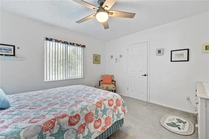 Bedroom featuring a textured ceiling, ceiling fan, and light carpet
