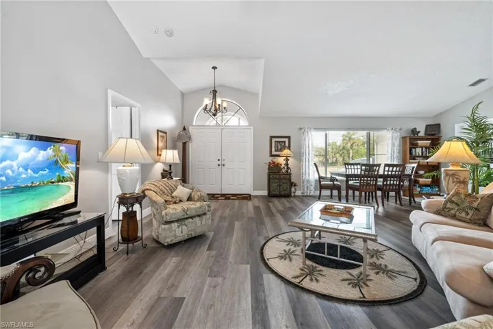 Living room featuring hardwood / wood-style flooring, vaulted ceiling, and an inviting chandelier