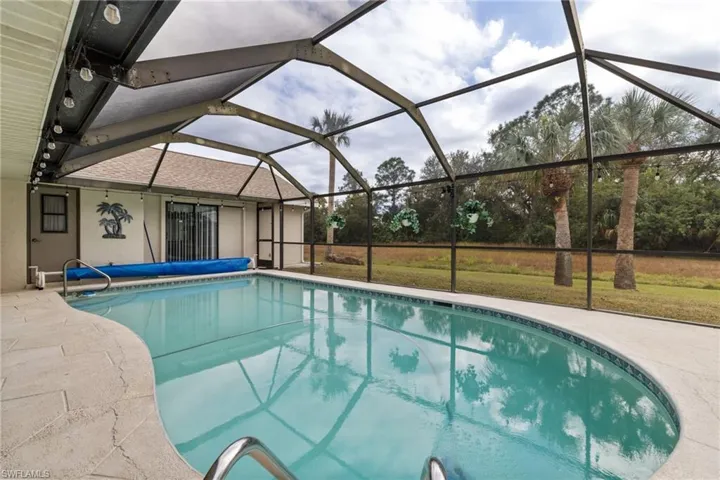 View of swimming pool with a patio, a lanai, and a lawn