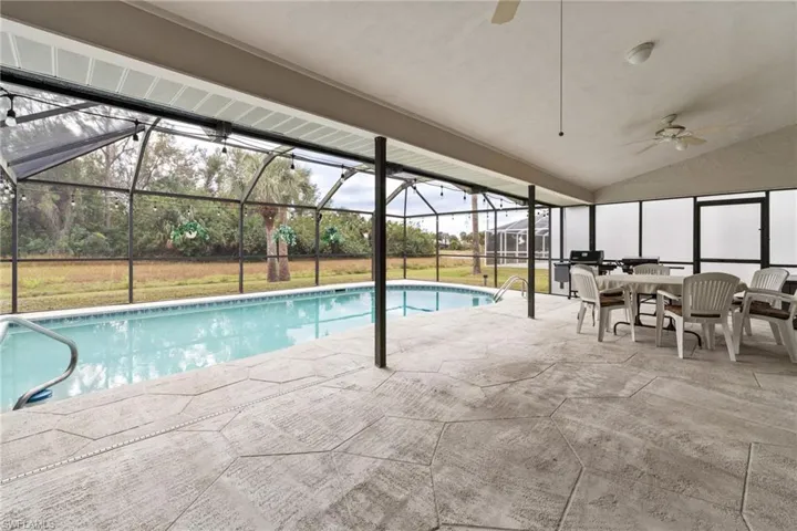 View of swimming pool featuring glass enclosure, ceiling fan, and a patio