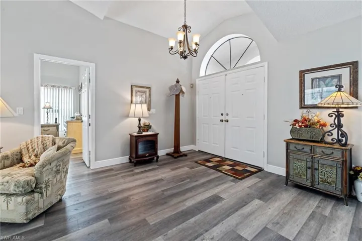Entrance foyer featuring a textured ceiling, dark hardwood / wood-style floors, lofted ceiling, and a notable chandelier