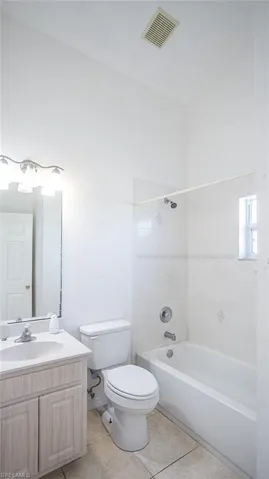 Bathroom with vanity, light tile patterned floors, and tub / shower combination