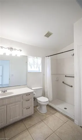 Bathroom with vanity, a shower stall, light tile patterned floors.