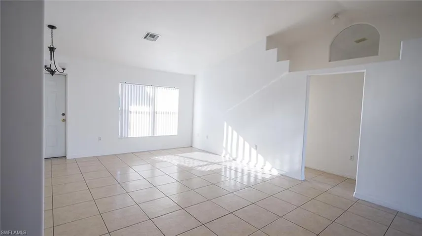 Empty room featuring light tile patterned floors and suspended lighting