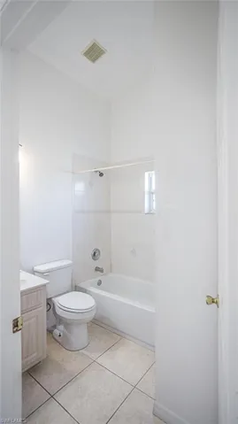 Bathroom with vanity, bathtub / shower combination, and light tile patterned floors