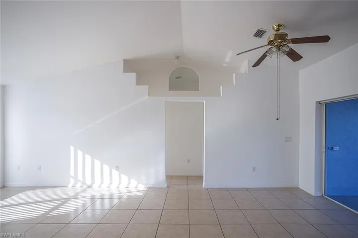 Unfurnished room featuring ceiling fan, lofted ceiling, and light tile patterned floors