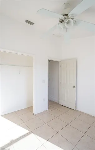 Unfurnished bedroom featuring a ceiling fan, light tile patterned floors, and a closet