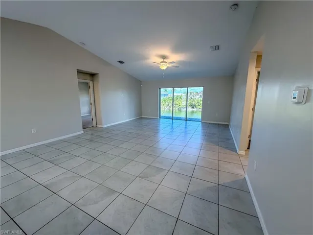 Spare room featuring light tile patterned flooring, a ceiling fan, and vaulted ceiling