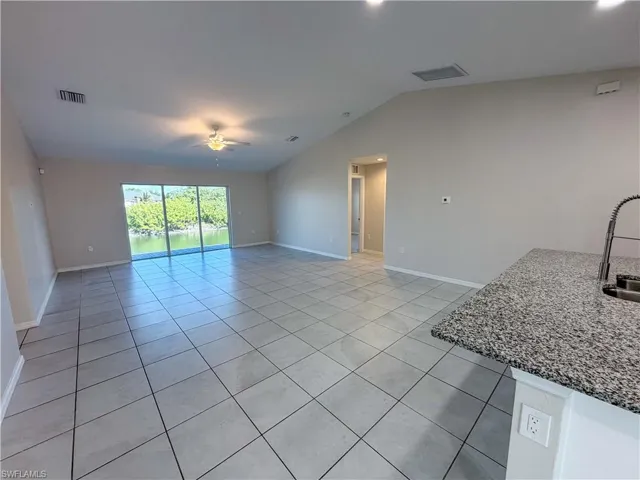 Unfurnished living room featuring light tile patterned floors, lofted ceiling, ceiling fan, and recessed lighting