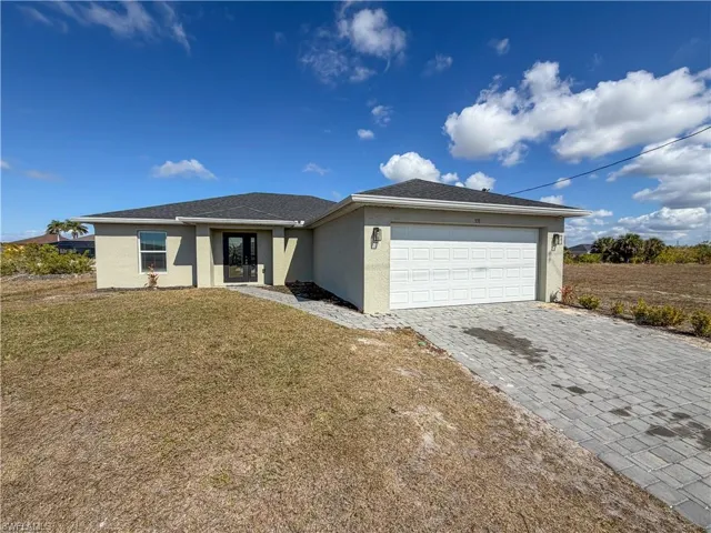 Ranch-style house featuring stucco siding, decorative driveway, a front yard, and a garage