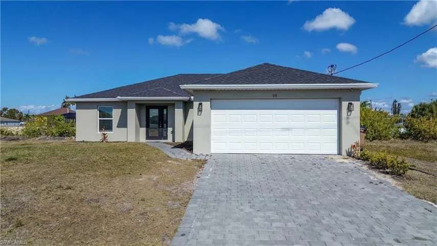 Single story home featuring stucco siding, decorative driveway, roof with shingles, a front lawn, and an attached garage