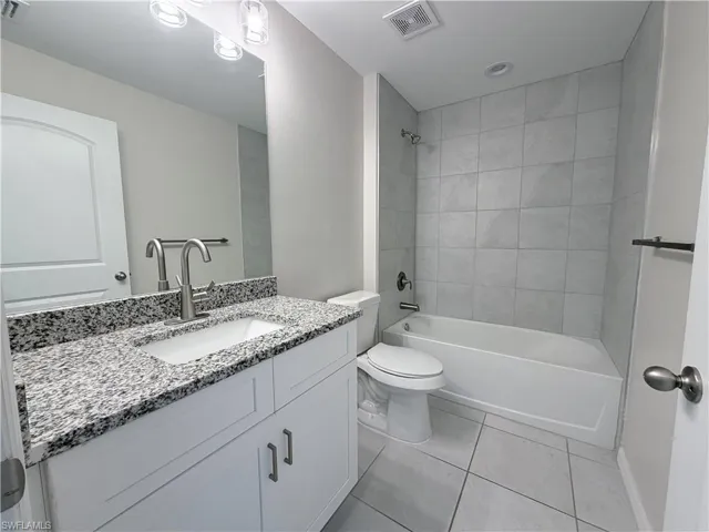 Bathroom featuring bathtub / shower combination, vanity, and light tile patterned floors