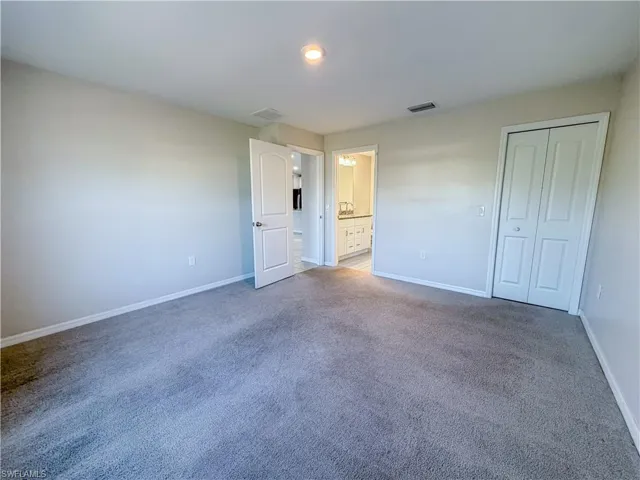 Unfurnished bedroom with carpet floors, ensuite bathroom, and a closet