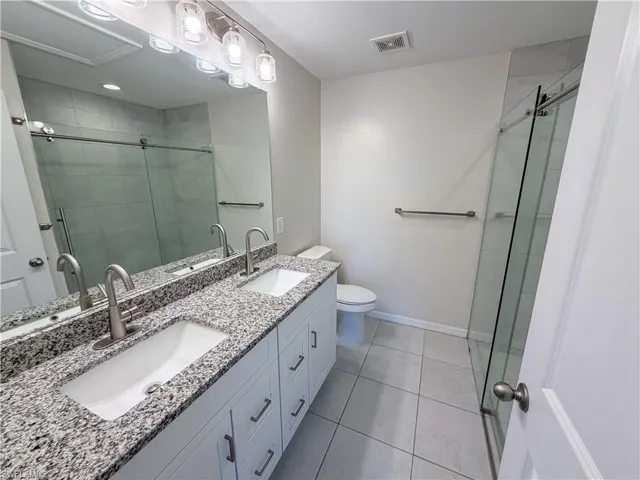 Full bathroom featuring double vanity, a shower stall, and light tile patterned floors