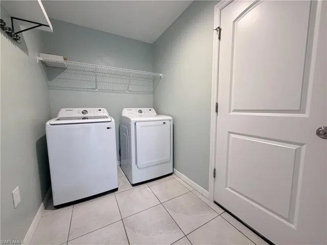 Laundry room with washing machine and clothes dryer and light tile patterned flooring