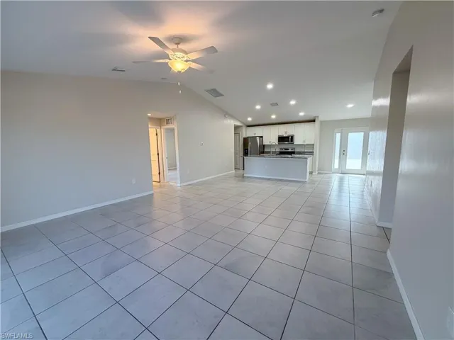 Unfurnished living room with light tile patterned flooring, a ceiling fan, vaulted ceiling, and recessed lighting