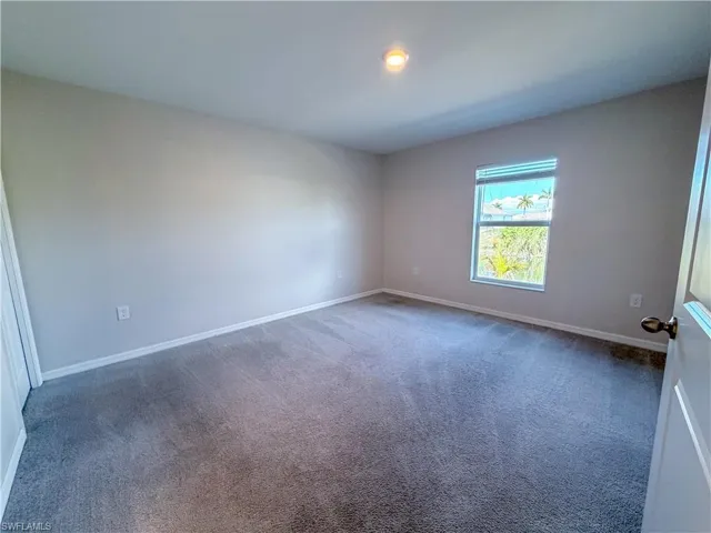 Carpeted spare room featuring baseboards