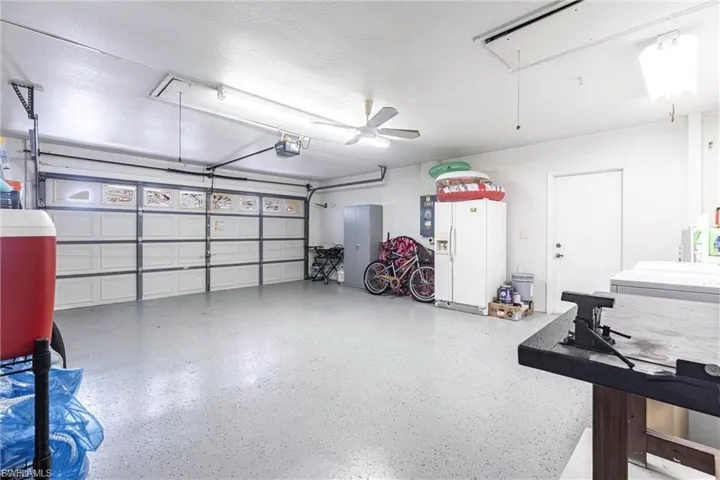 Garage featuring white fridge with ice dispenser and a garage door opener