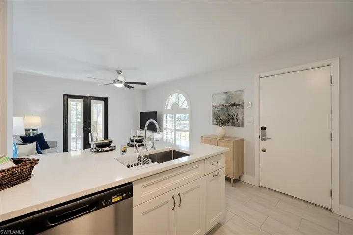 Kitchen with white cabinetry, dishwasher, sink, and ceiling fan